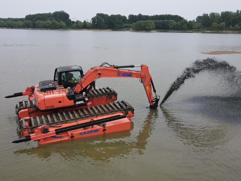 Une excavatrice amphibie équipée de pontons travaille dans le lac et la rivière