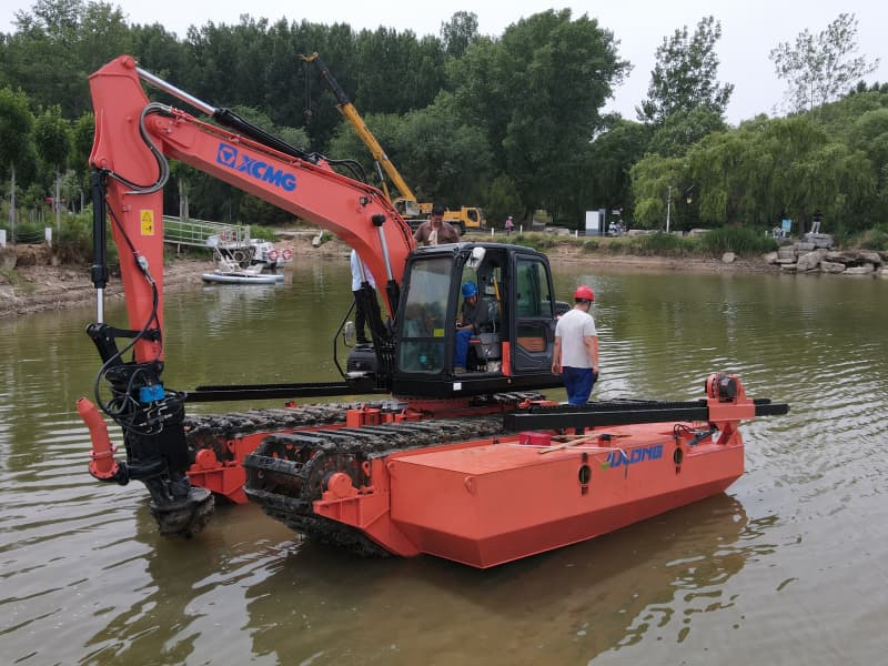Une excavatrice amphibie équipée de pontons travaille dans le lac et la rivière